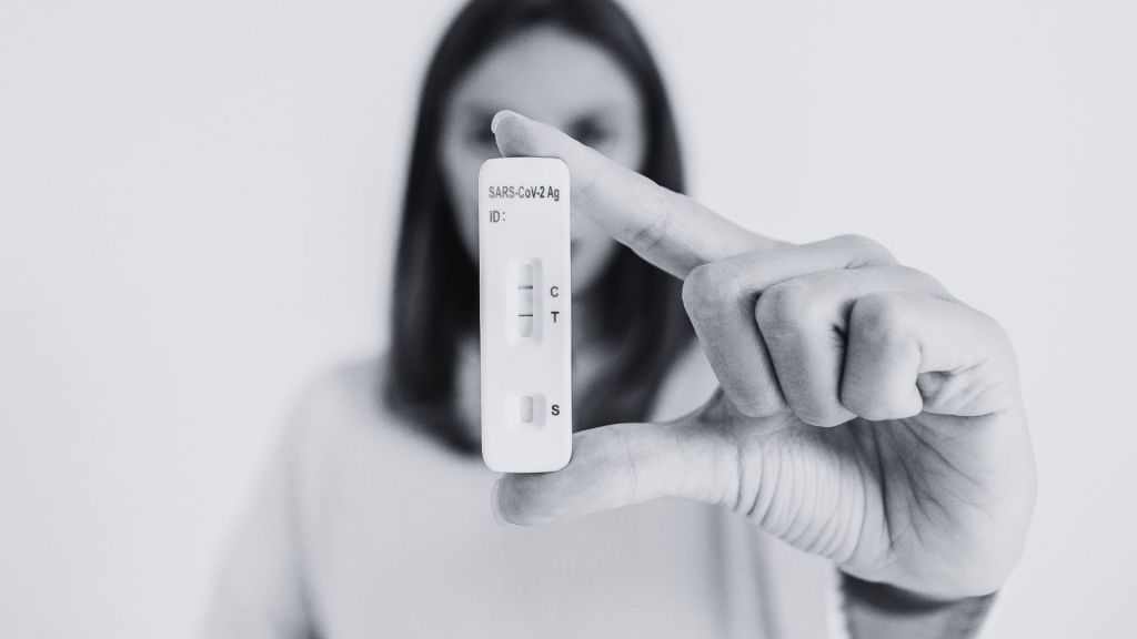 une femme tient entre deux doigts un test covid positif