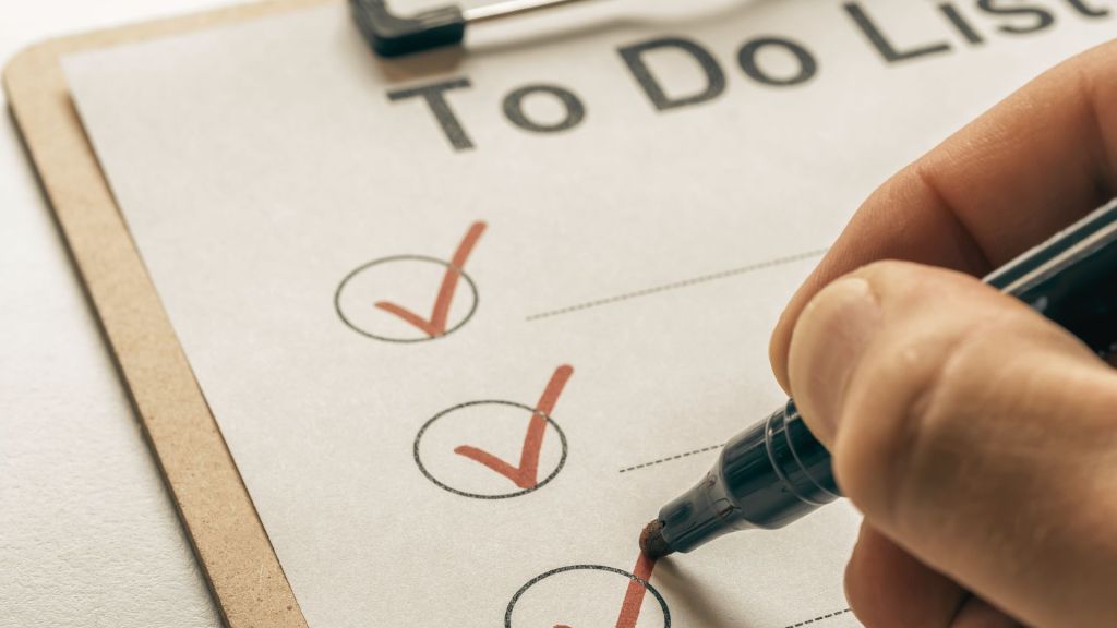 une main coche les items d'une to do list