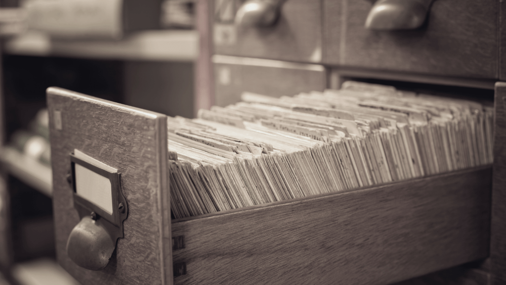 tiroir ouvert d'un vieux meuble, laissant apparaître de multiples fiches d'archives.