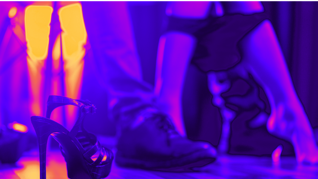 scène suggérant l'acte sexuel, on y voit deux jambes vétues et deux autres nues, sauf une culotte tombée sur les chevilles. Au premier plan une chaussure à talon haut.